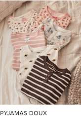 Une collection de pyjamas doux et confortables aux motifs et couleurs variés, notamment des rayures, des pois et des motifs floraux, disposés sur une surface texturée de couleur claire.