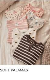A collection of soft, cozy pajamas in various patterns and colors, including stripes, polka dots, and floral designs, arranged on a textured, light-colored surface.