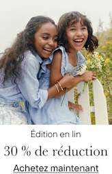 Deux jeunes femmes aux cheveux bouclés s'enlacent et rient joyeusement dans un champ de fleurs.