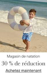 Un jeune garçon tient avec enthousiasme un gilet de sauvetage à rayures blanches et bleues sur une plage de sable fin, l'océan étant visible en arrière-plan.