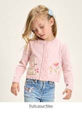 Une jeune fille portant un pull rose brodé de motifs floraux et animaliers, se détachant sur un fond uni.