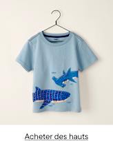 Un t-shirt bleu clair orné d'un dessin représentant deux requins bleus et des petits poissons est accroché à un cintre sur un fond blanc uni.