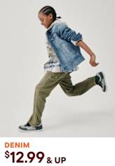 A person wearing a denim jacket and cargo pants is jumping and moving dynamically against a plain white background.