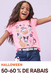 Une jeune fille aux cheveux longs et bouclés sourit et porte un t-shirt rose avec des personnages de dessins animés colorés imprimés dessus, debout sur un fond uni.