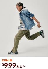 A person wearing a denim jacket and cargo pants is jumping and moving dynamically against a plain white background.