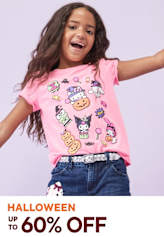 A young girl with long, curly hair is smiling and wearing a pink t-shirt with colorful cartoon characters printed on it, standing against a plain background.