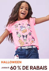Une jeune fille aux cheveux longs et bouclés sourit et porte un t-shirt rose avec des personnages de dessins animés colorés imprimés dessus, debout sur un fond uni.