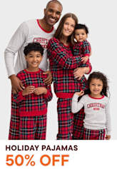 A happy family wearing matching plaid pajamas stands together in a studio setting, with a "Holiday Pajamas 50% Off" promotional text overlaid on the image.