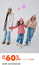 Three young girls wearing warm winter outfits, including puffy jackets and hats, stand together against a plain white background. The girls appear to be smiling and holding hands, creating a cheerful and playful scene.