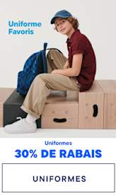 L'image montre une jeune femme souriante, portant des lunettes, un pull bleu marine et un pantalon kaki, assise sur un tabouret et tenant une paire de chaussures noires. Le fond est une surface blanche unie sur laquelle on peut lire en évidence « Uniform Faves » et « Uniforms -30 % ».