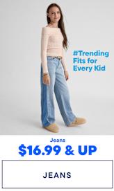 The image features three young girls wearing trendy casual outfits, including jeans, and interacting with each other in a playful manner against a plain background with a "#Trending Fits for Every Kid" text overlay.