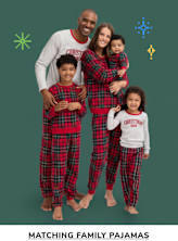 A family of five wearing matching red and black plaid pajamas stands in front of a green background with festive holiday decorations.