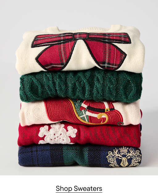 A stack of five colorful holiday sweaters sits against a plain, light gray background.