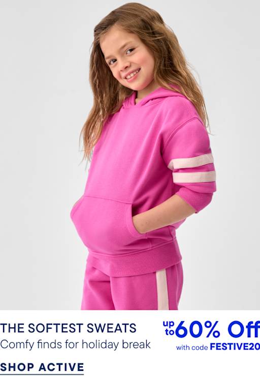 A young girl wearing a bright pink hoodie and matching sweatpants stands against a plain light gray background.