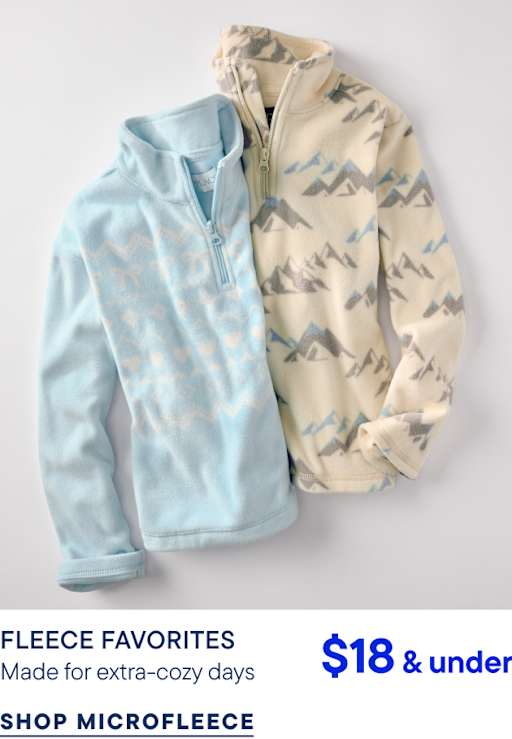 Two fleece pullovers, one light blue and one cream with a mountain pattern, lie against a plain white background.