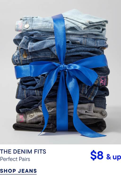 Una pila de pantalones vaqueros doblados en diferentes tonos de azul y gris está atada con una cinta azul brillante sobre un fondo gris claro liso.