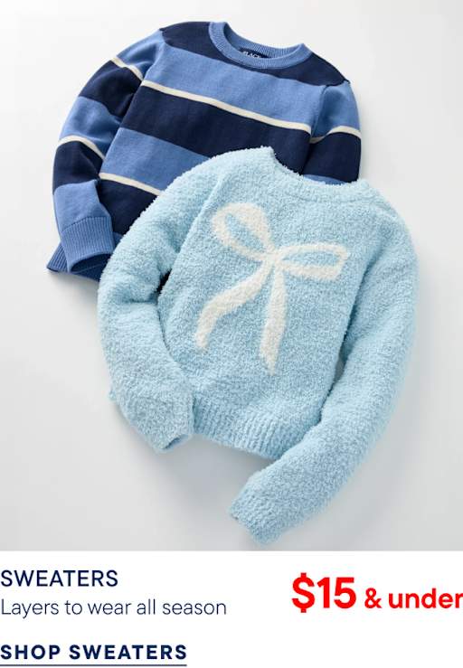 A light blue fuzzy sweater with a white bow sits atop a navy and blue striped sweater against a plain white background.