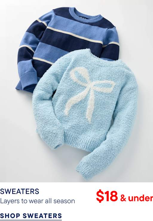 A light blue fuzzy sweater with a white bow sits atop a navy and blue striped sweater against a plain white background.