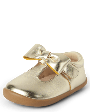 Un par de zapatos de cuero de color dorado con un detalle de lazo en la parte delantera, sobre un fondo blanco liso.