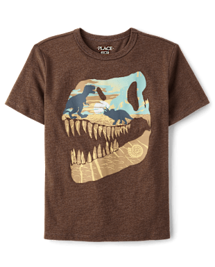 Una camiseta marrón con un gráfico colorido que representa el cráneo de un dinosaurio sobre un fondo de paisaje desértico.