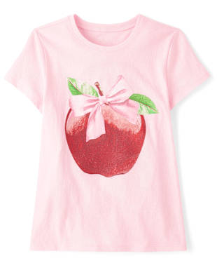 Una camiseta rosa con un gráfico grande y vibrante de una manzana roja adornada con un lazo rosa en la parte delantera.