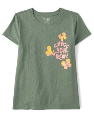 La camiseta presenta un diseño gráfico colorido de mariposas con el texto "Persigue tus sueños" impreso sobre un fondo verde.