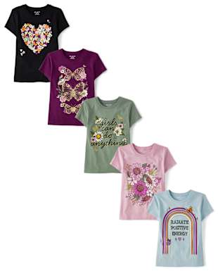 La imagen muestra una colección de camisetas coloridas y estampadas con diversos diseños, incluidos motivos florales, lazos de lentejuelas y un gráfico con temática de arcoíris.