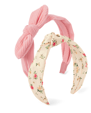 La imagen muestra una diadema rosa con un lazo de tela con estampado floral adherido a ella, sobre un fondo blanco liso.