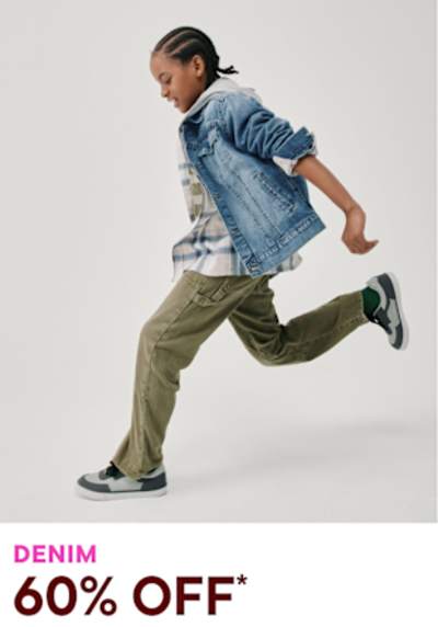 A person wearing a denim jacket and cargo pants is running or jumping in the foreground, against a plain white background.