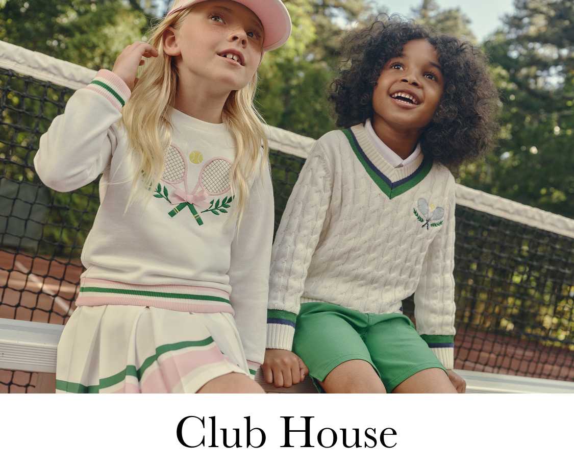 Dos mujeres jóvenes, una rubia y la otra oscura y rizada, están de pie en una cancha de tenis, sonriendo a la cámara. Al fondo se ve un exuberante entorno verde con árboles y vegetación.