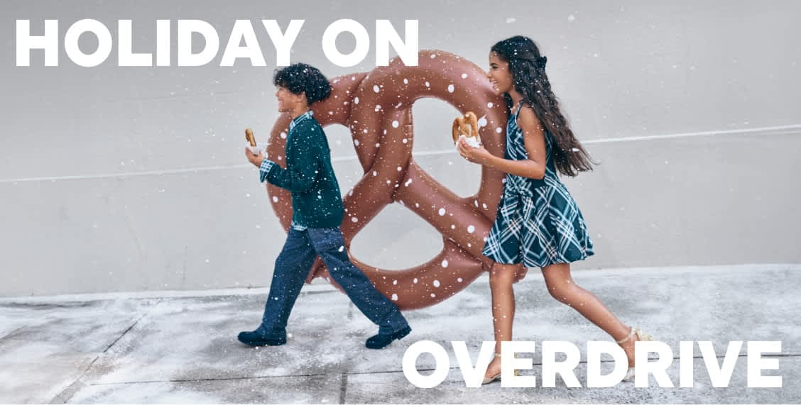 The image features three young women wearing casual, colorful clothing and posing together in front of a plain background. The women appear to be interacting with each other in a friendly and lively manner.