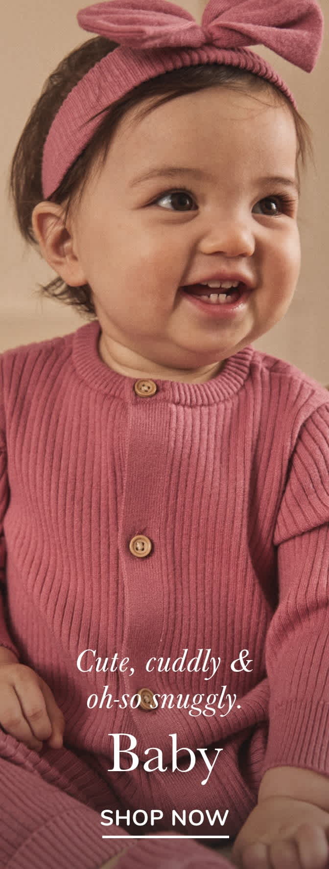 A smiling baby wearing a pink sweater with the text "Cute, cuddly & oh-so snuggly" against a plain background.
