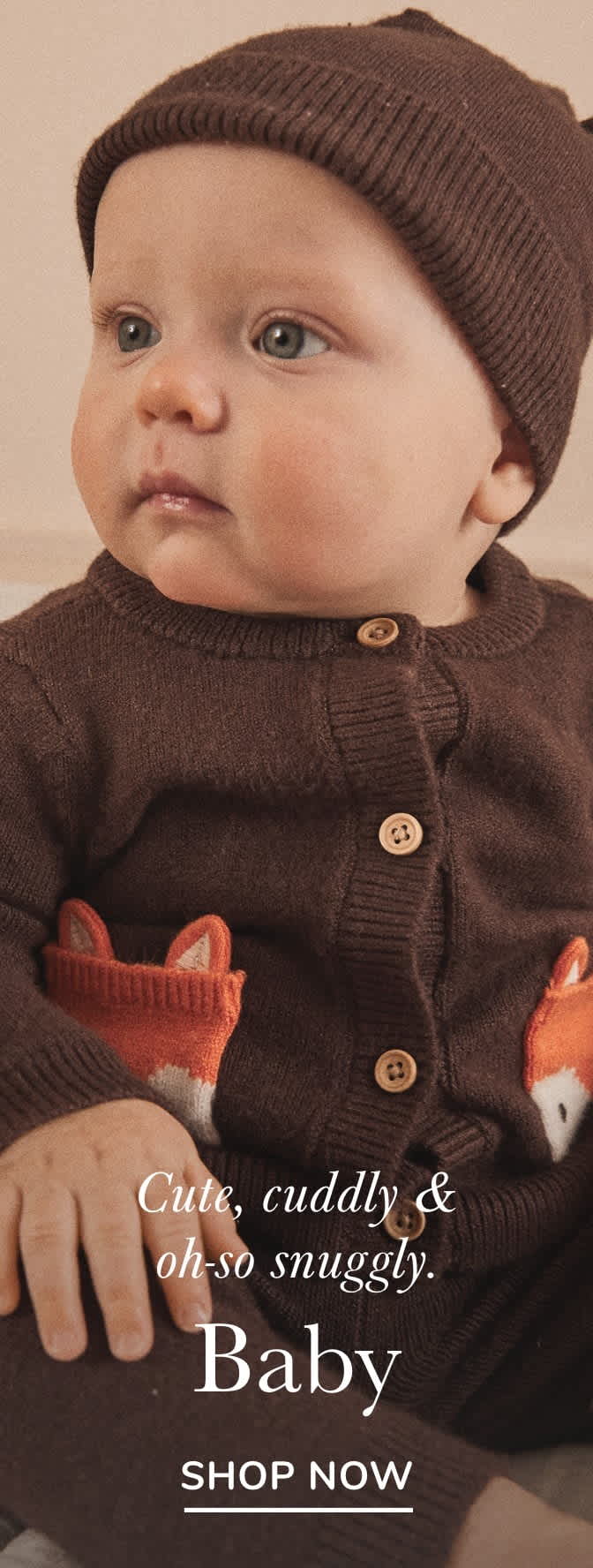 A close-up of a baby wearing a brown knitted hat and sweater, with a text overlay describing the baby as "Cute, cuddly & oh-so snuggly."