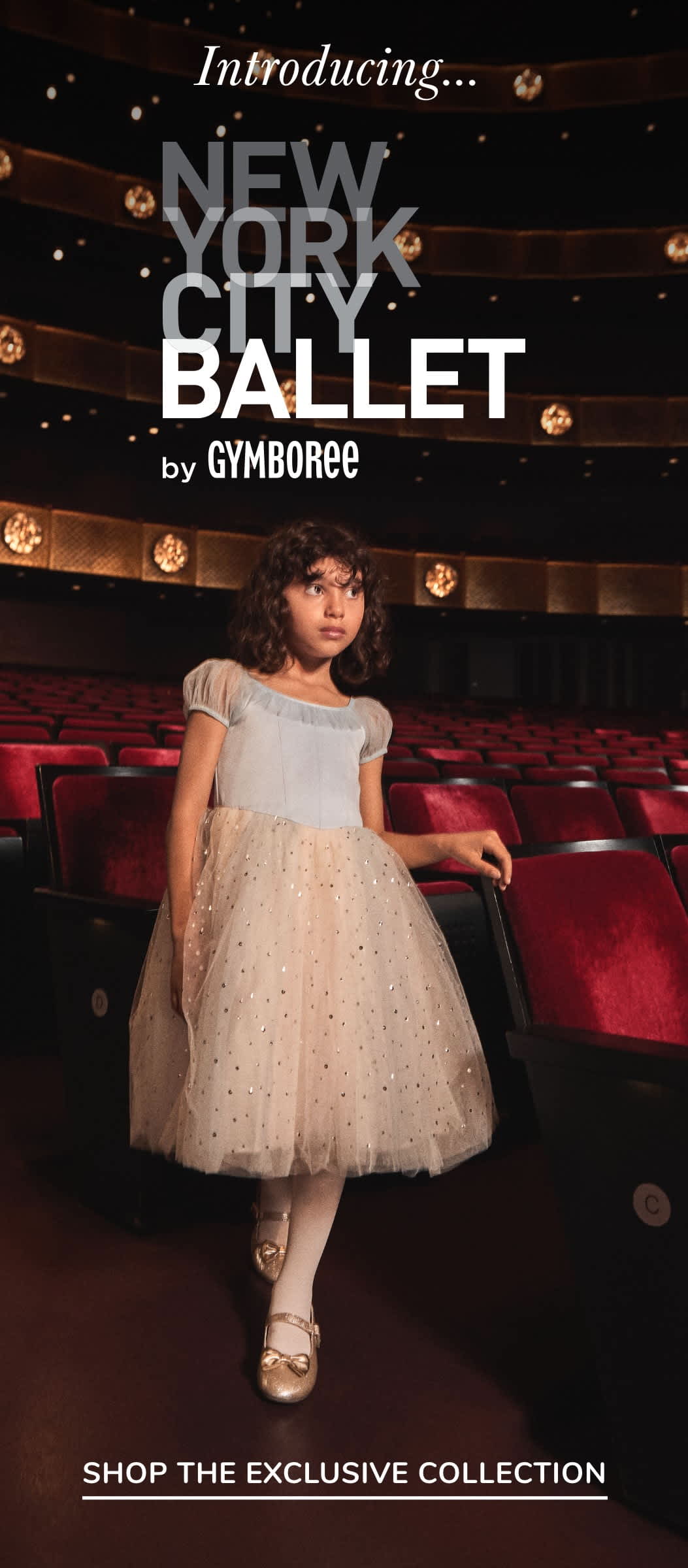 Una joven con un vestido de tul blanco se encuentra en un escenario con el logotipo "New York City Ballet by Gymboree" visible en el fondo.
