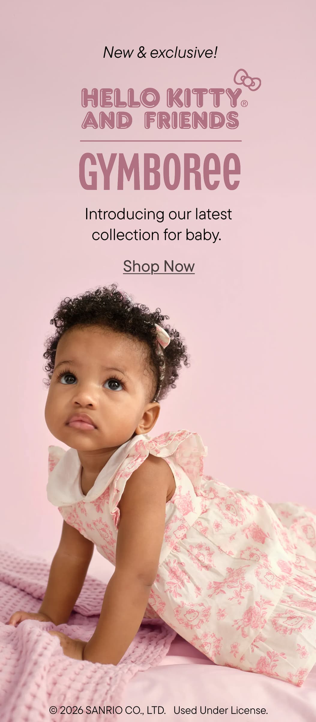 Una niña sonriente con un vestido floral rosa y blanco se sienta sobre un fondo rosa con el texto "Hello Kitty y sus amigos Gymboree" promocionando una nueva colección para bebés.