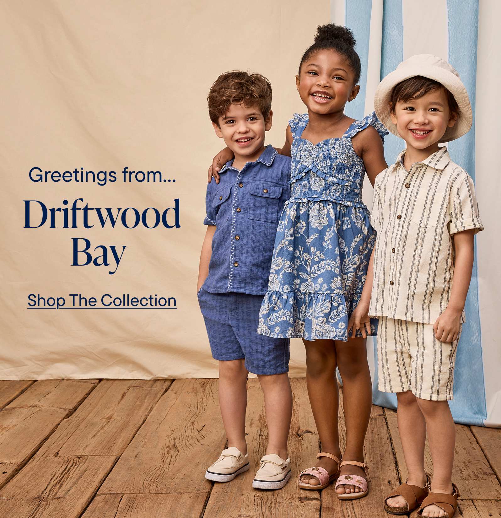 Two young girls, one with curly hair and the other with a dress, are standing on a sandy beach with the ocean and a clear sky in the background.