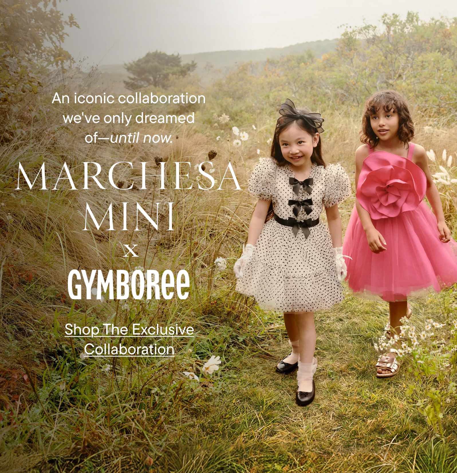 Two young girls in colorful dresses stand in a field with trees and mountains in the background, showcasing an iconic collaboration between Marchesa Mini and Gymboree.