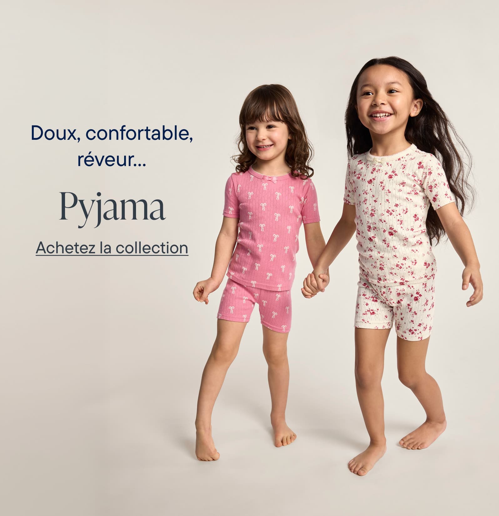Doux, confortables, oniriques… Les pyjamas. L’image présente deux jeunes filles portant des pyjamas assortis, l’un à pois roses et l’autre à motifs floraux. Elles se détachent sur un fond clair et uni, créant une image simple et accueillante.