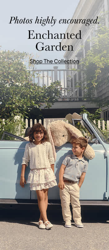 The image shows two young children, a girl and a boy, standing in front of a vintage-style van with the text "Enchanted Garden" displayed prominently on the background.