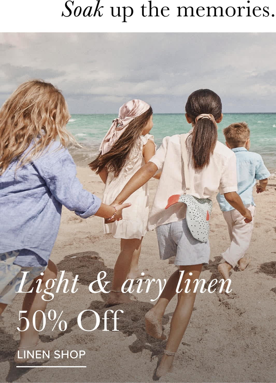 The image shows a group of people, likely women, walking along a beach with the ocean in the background. They are wearing light, airy linen clothing and appear to be enjoying the beach setting.