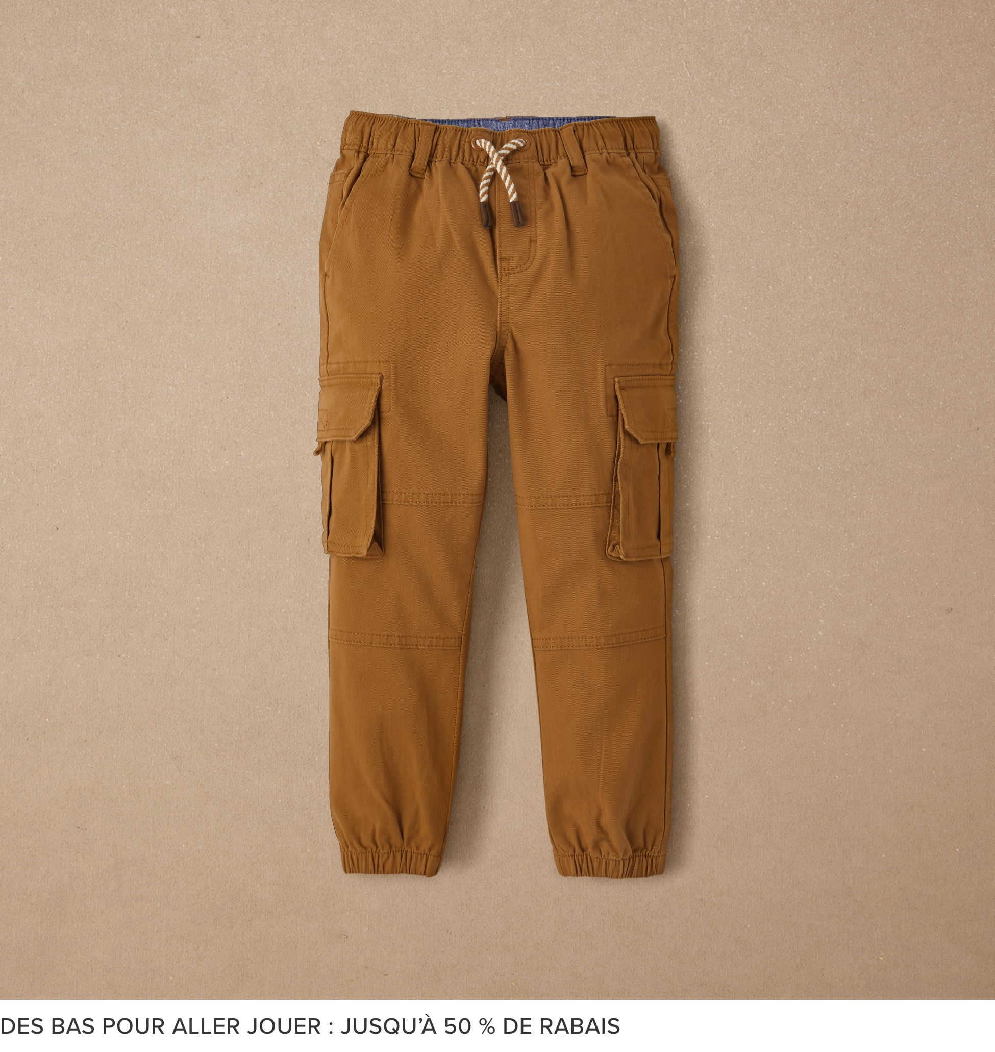 A pair of tan cargo pants with drawstring waist and pockets, against a plain beige background.