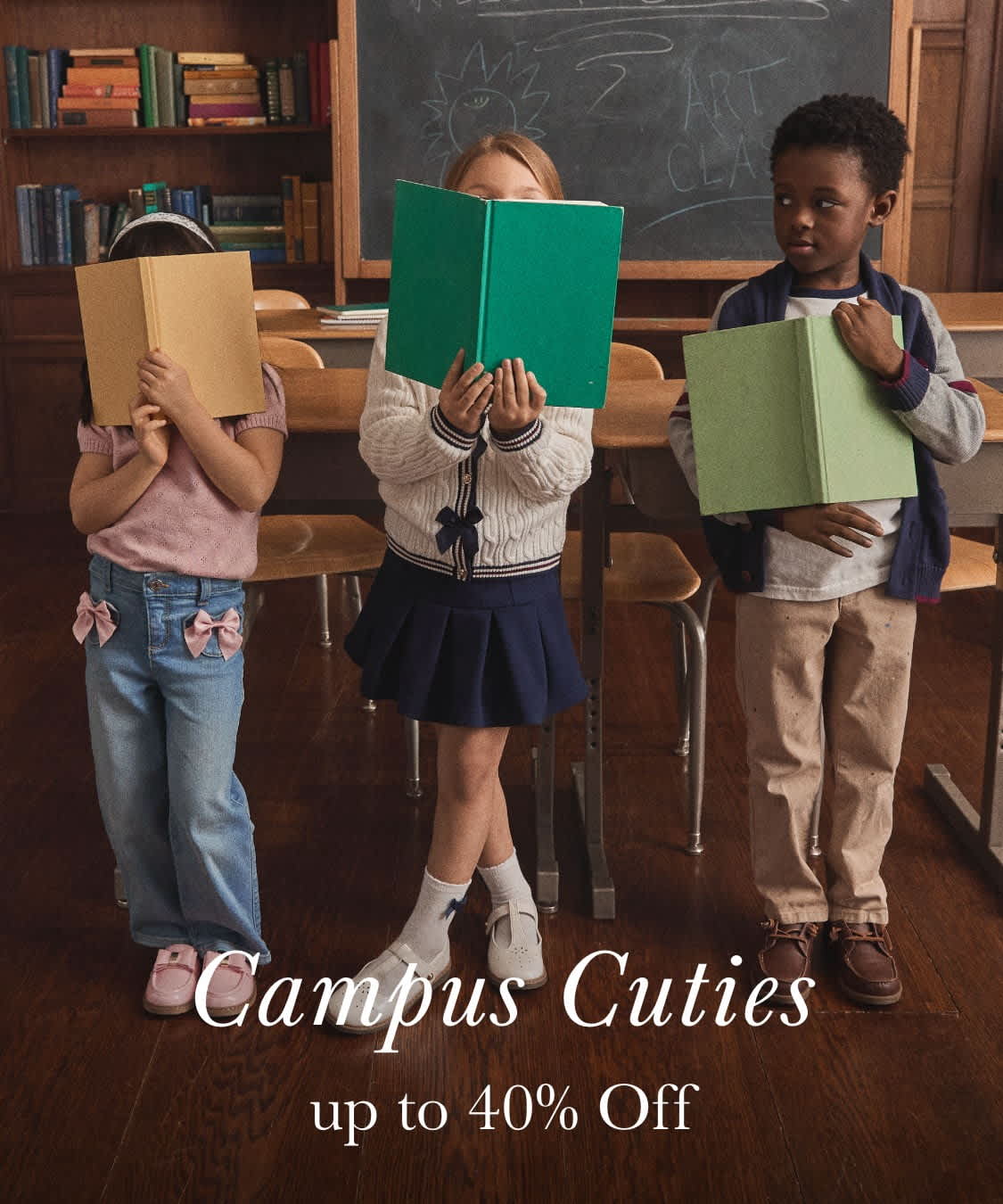 The image shows two young students, a boy and a girl, holding up green folders in what appears to be a classroom setting, with a chalkboard and a globe visible in the background.