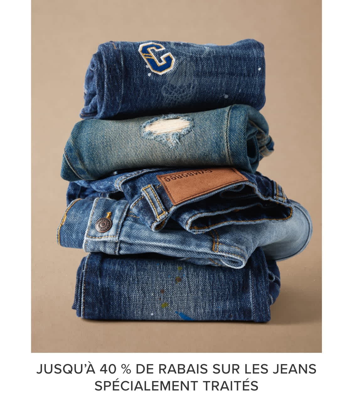 A stack of various denim clothing items, including jeans, jackets, and shirts, against a beige background.