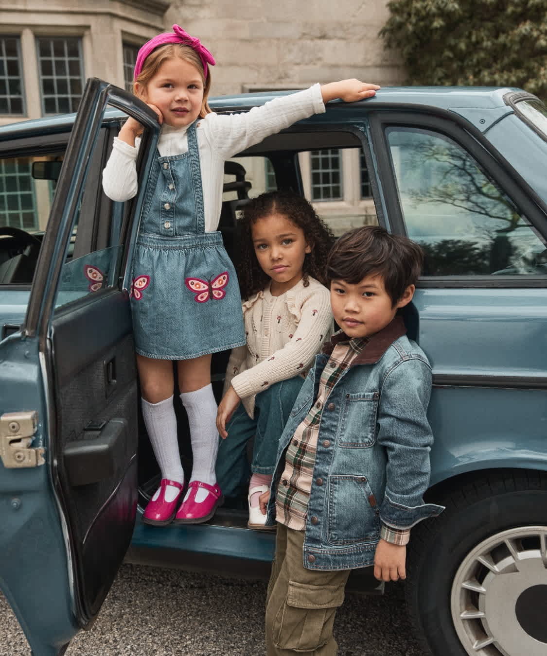The image shows three young people, two girls and one boy, standing in front of a large, ornate stone building with a sign that reads "Adventures start here" and offers a 30% discount.