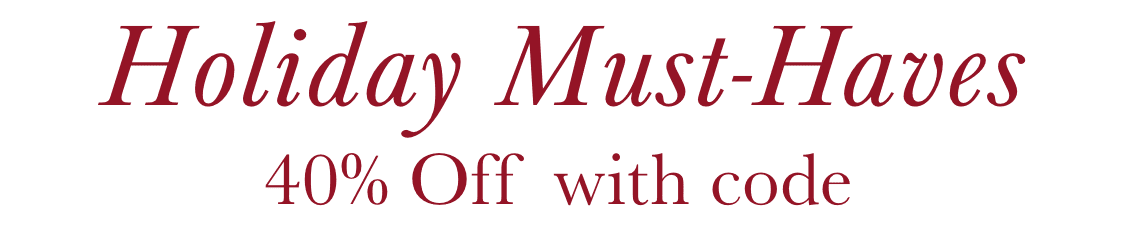 Una niña pequeña con el pelo rizado sonríe y lleva un jersey de rayas con dibujos de pingüinos, de pie frente a una pared de piedra.