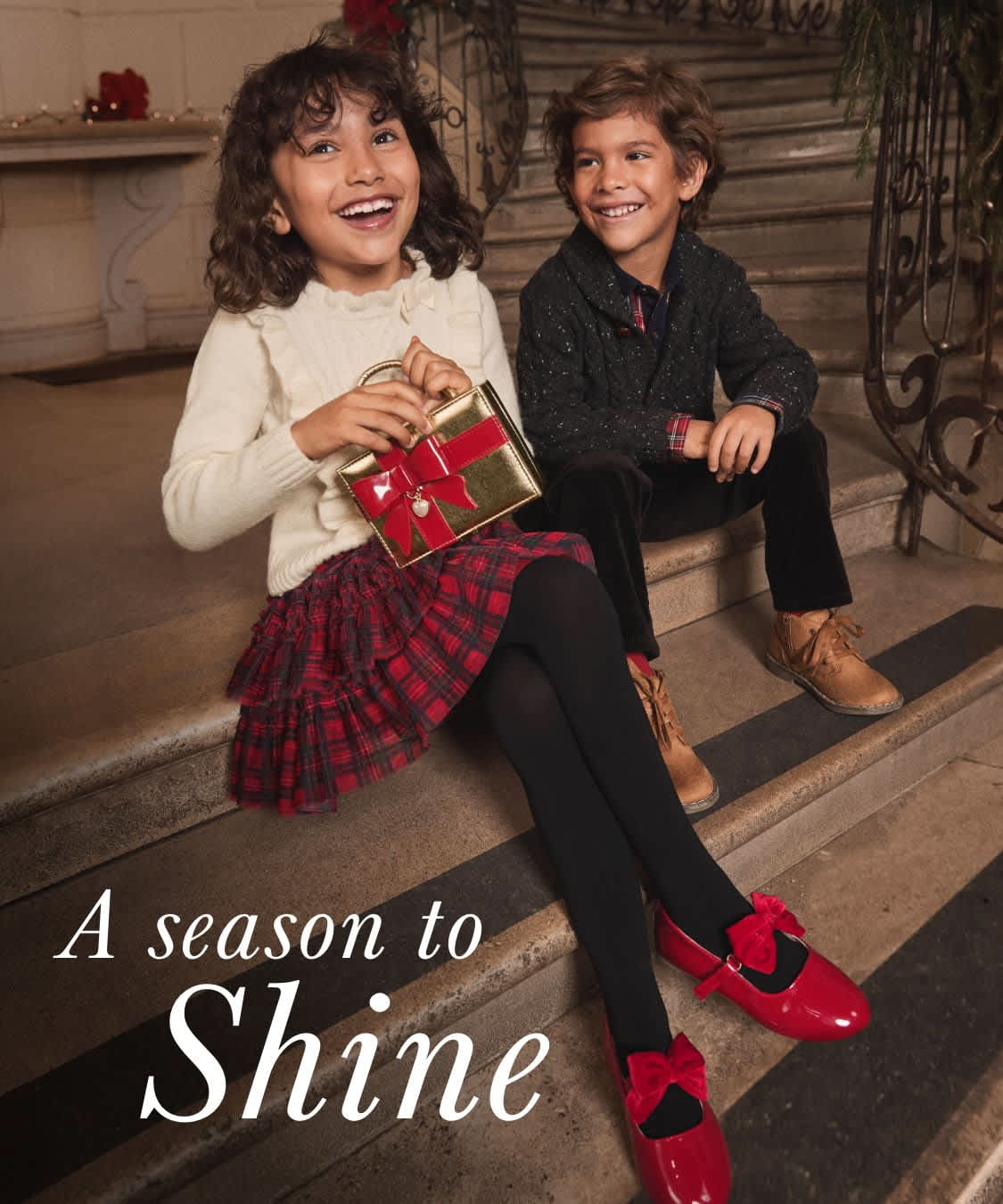 Two young women dressed in festive holiday attire are walking down a decorated street, surrounded by holiday decorations and lights.