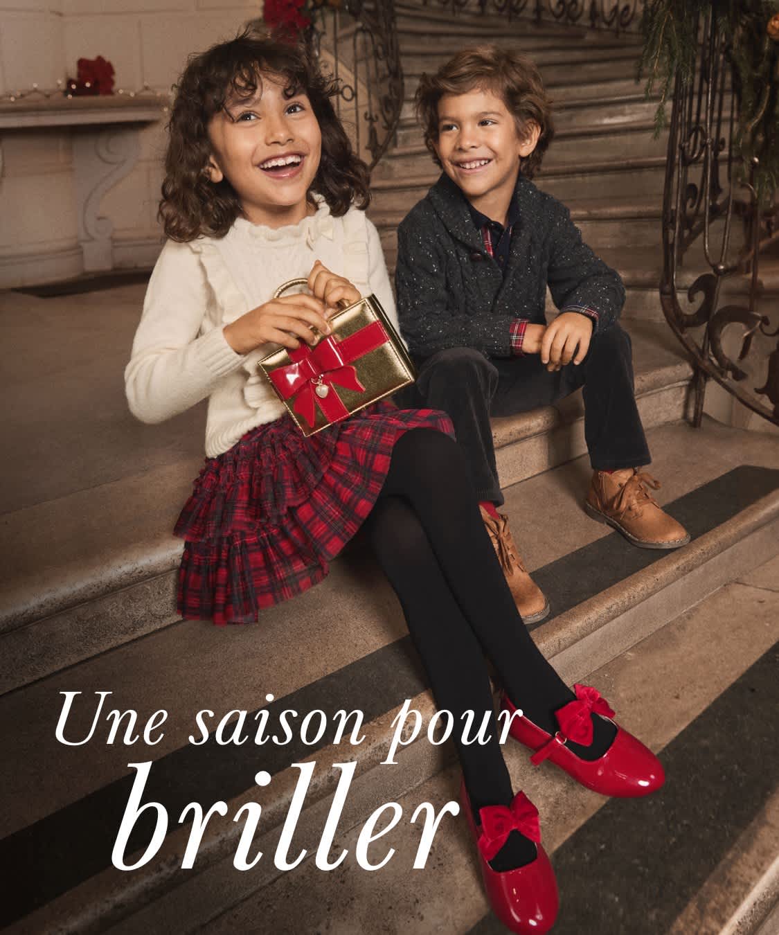 Deux jeunes femmes vêtues de tenues de fête se tiennent dans un couloir décoré, entourées de décorations et de lumières de Noël.