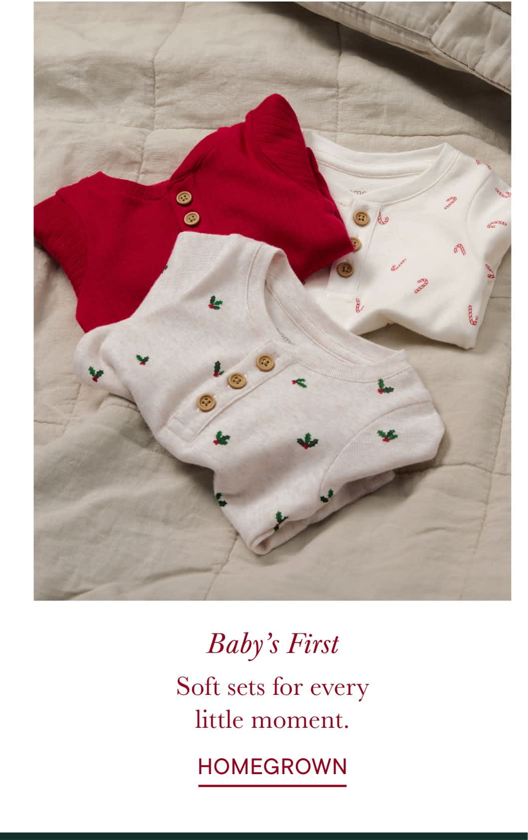 Soft, cozy baby clothes in red and white patterns lie on a light-colored bedsheet, accompanied by a text overlay describing them as "Baby's First Soft sets for every little moment."