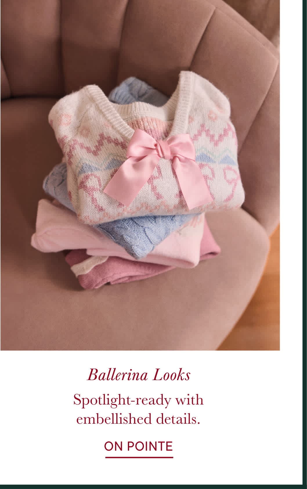 The image shows a stack of neatly folded pink and gray patterned clothing, adorned with a delicate pink bow, resting on a soft, beige surface.