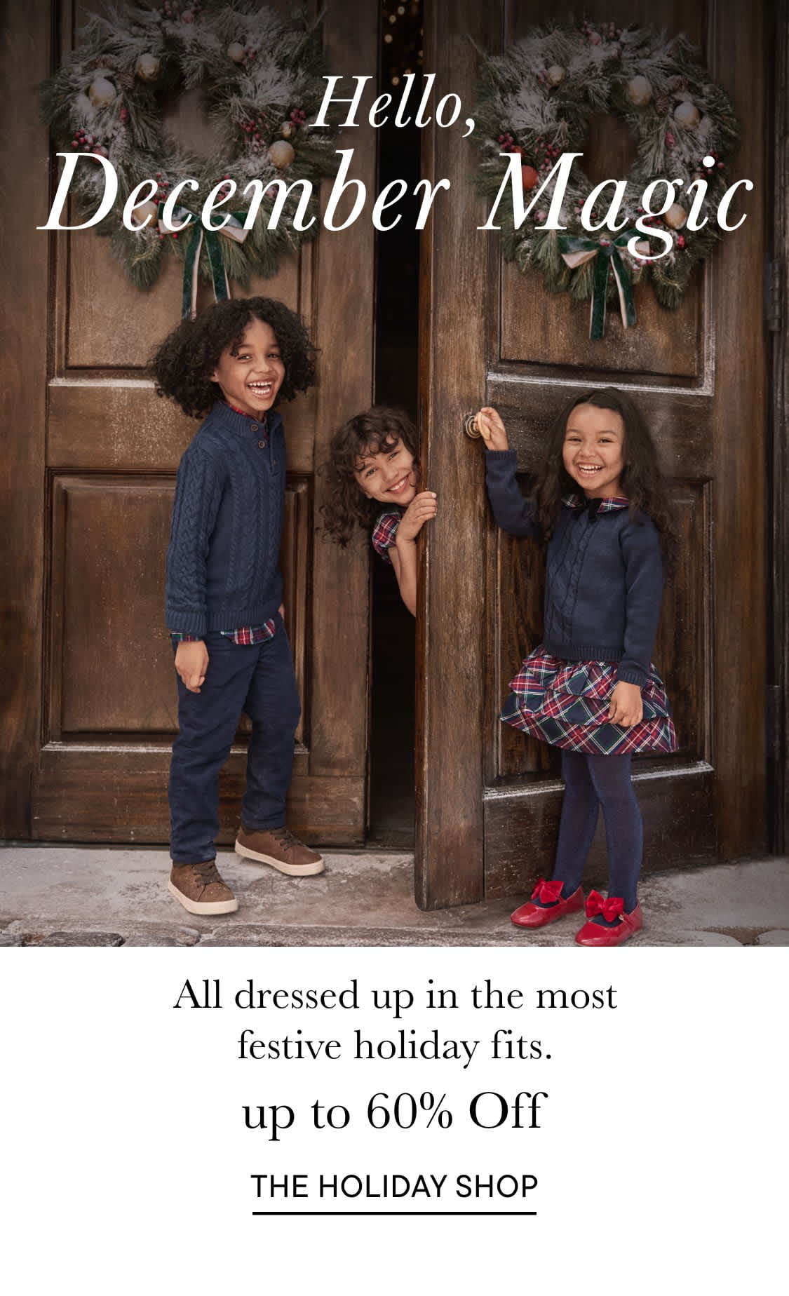 The image shows three young women dressed in festive holiday attire, standing in front of a wooden door decorated with holiday garlands and a sign that reads "Hello, December Magic".